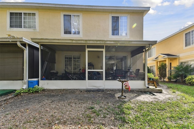 rear view of property with a sunroom and stucco siding