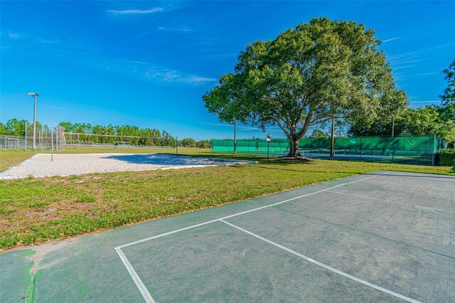 exterior space with a tennis court, fence, a lawn, and volleyball court