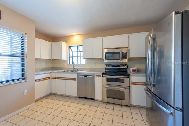 kitchen with light tile patterned floors, white cabinetry, appliances with stainless steel finishes, and light countertops