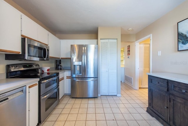 kitchen with appliances with stainless steel finishes, light countertops, white cabinets, and light tile patterned floors