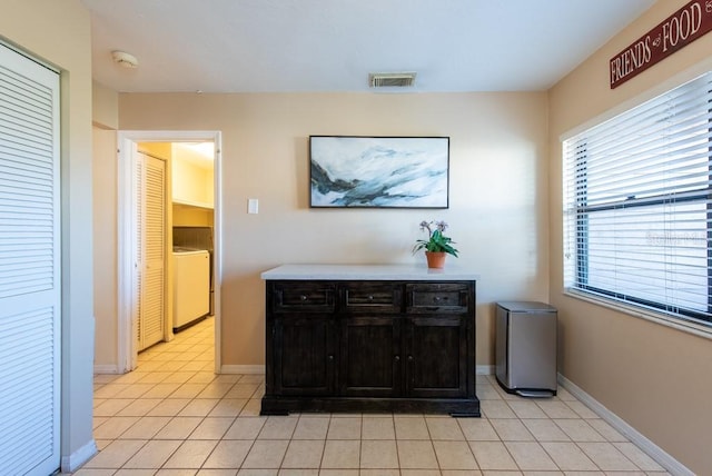 corridor with washer / dryer, visible vents, baseboards, and light tile patterned floors