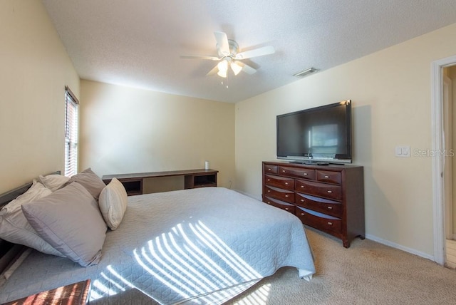 bedroom featuring light colored carpet, visible vents, a ceiling fan, a textured ceiling, and baseboards