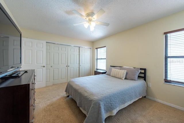 bedroom with light carpet, baseboards, ceiling fan, a textured ceiling, and a closet