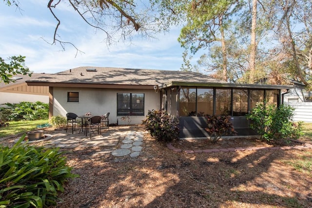 back of house featuring a sunroom, stucco siding, and a patio