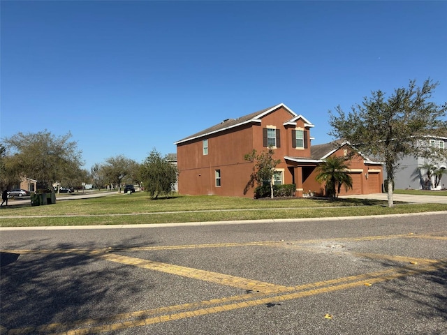 view of front of property with a garage, concrete driveway, a front lawn, and stucco siding