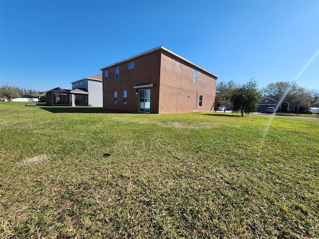 rear view of property featuring a yard and stucco siding