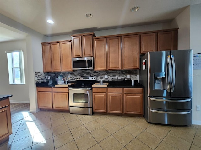 kitchen with light tile patterned floors, recessed lighting, appliances with stainless steel finishes, tasteful backsplash, and brown cabinetry