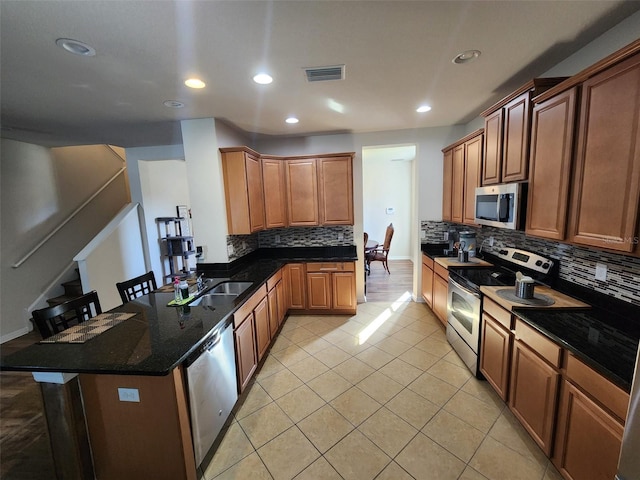 kitchen with light tile patterned floors, tasteful backsplash, visible vents, appliances with stainless steel finishes, and a peninsula