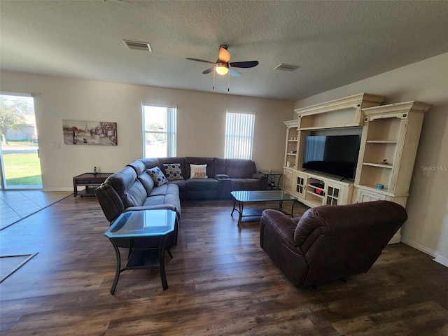 living area featuring a ceiling fan, a textured ceiling, visible vents, and dark wood-style flooring