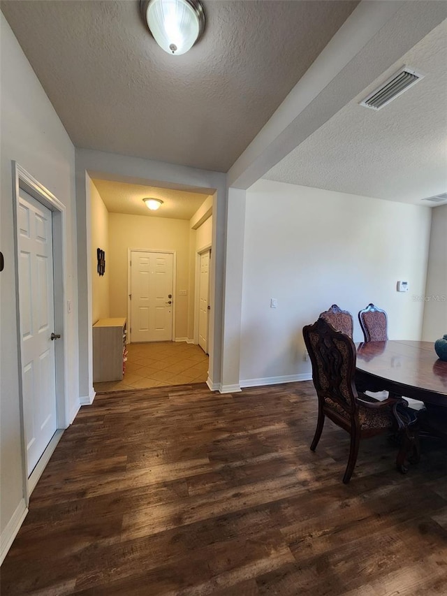 dining space with visible vents, a textured ceiling, baseboards, and wood finished floors