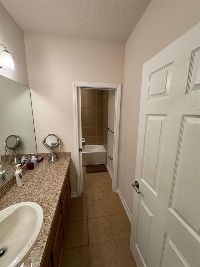 full bathroom with a textured ceiling, vanity, baseboards, a bath, and tile patterned floors