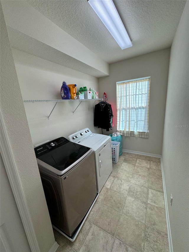 laundry area with laundry area, a textured ceiling, baseboards, and separate washer and dryer