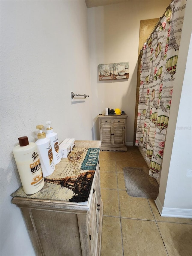 full bath with a shower with curtain, tile patterned flooring, and baseboards