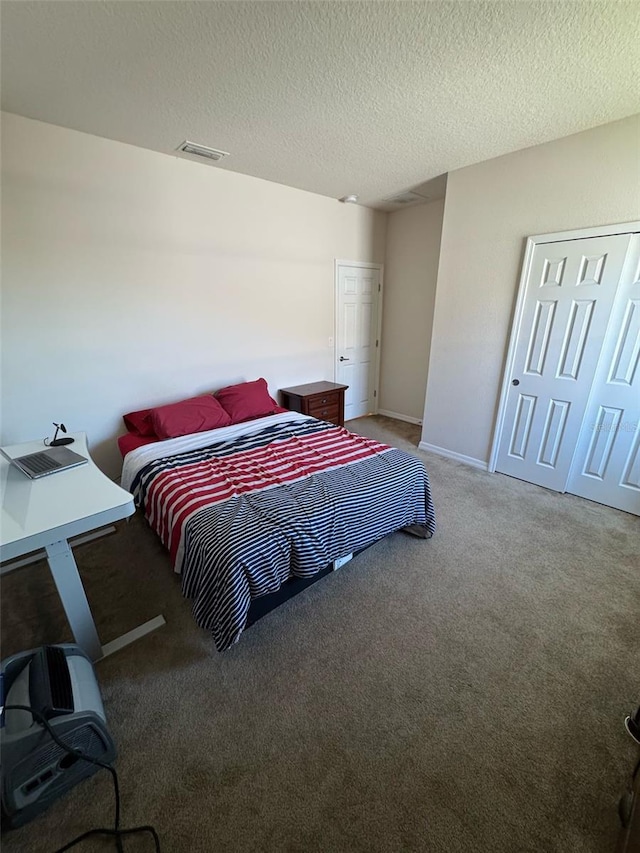 bedroom with a textured ceiling, carpet flooring, visible vents, and baseboards