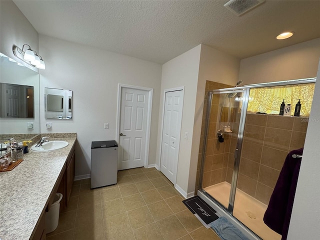 bathroom with a stall shower, visible vents, tile patterned flooring, a textured ceiling, and vanity