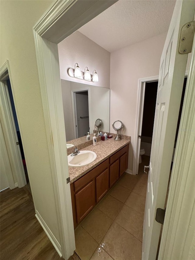 bathroom with tile patterned flooring, toilet, a textured ceiling, and vanity