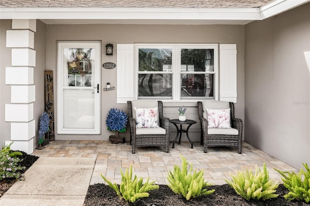 entrance to property featuring a shingled roof and stucco siding