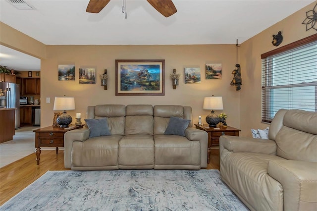 living room featuring light wood-style flooring, visible vents, and ceiling fan