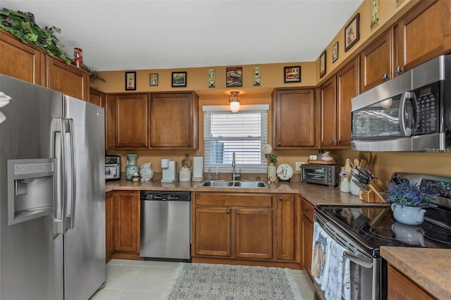 kitchen with brown cabinets, light tile patterned floors, stainless steel appliances, light countertops, and a sink