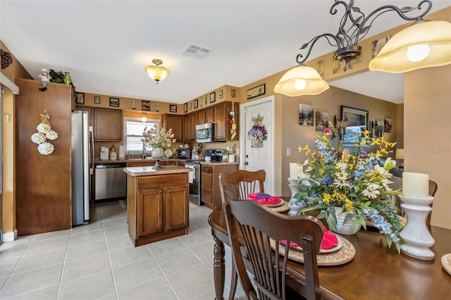 kitchen featuring visible vents, appliances with stainless steel finishes, brown cabinets, a center island, and light countertops