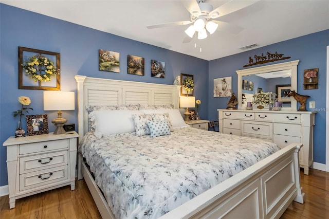 bedroom featuring baseboards, visible vents, ceiling fan, and wood finished floors