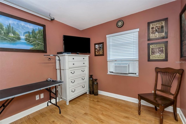 living area featuring light wood-style floors, baseboards, and cooling unit