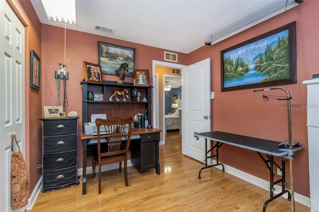 office area with light wood-type flooring, visible vents, and baseboards