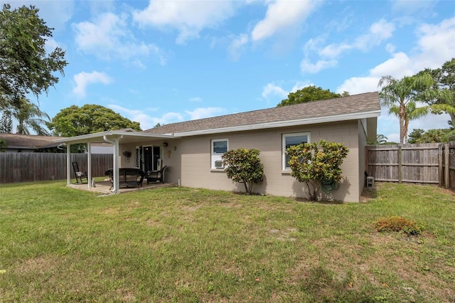 back of house with a patio area, a fenced backyard, a lawn, and concrete block siding