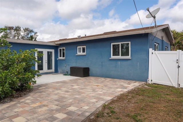 back of house featuring french doors, stucco siding, a gate, a patio area, and fence