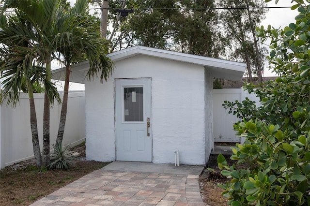 doorway to property featuring fence and stucco siding