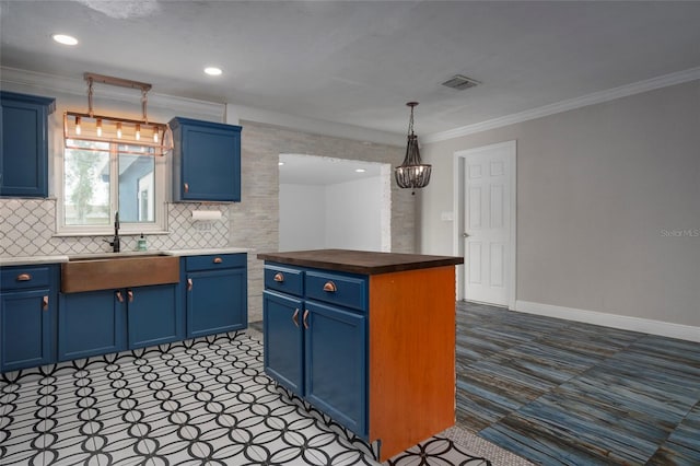 kitchen featuring dark countertops, a center island, blue cabinets, pendant lighting, and a sink