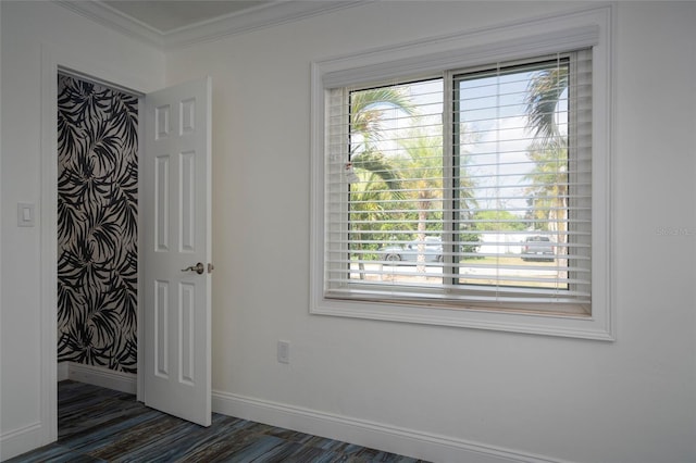 unfurnished room featuring dark wood-style flooring, ornamental molding, a healthy amount of sunlight, and baseboards