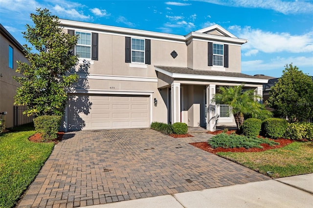 traditional-style house featuring decorative driveway, an attached garage, and stucco siding