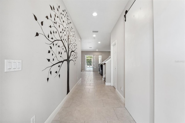 corridor with recessed lighting, visible vents, a barn door, light tile patterned flooring, and baseboards