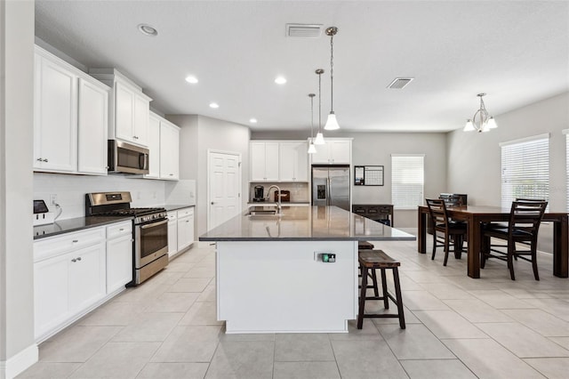 kitchen featuring appliances with stainless steel finishes, light tile patterned flooring, a sink, and visible vents