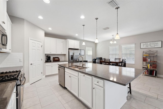 kitchen with stainless steel appliances, a sink, visible vents, white cabinets, and backsplash