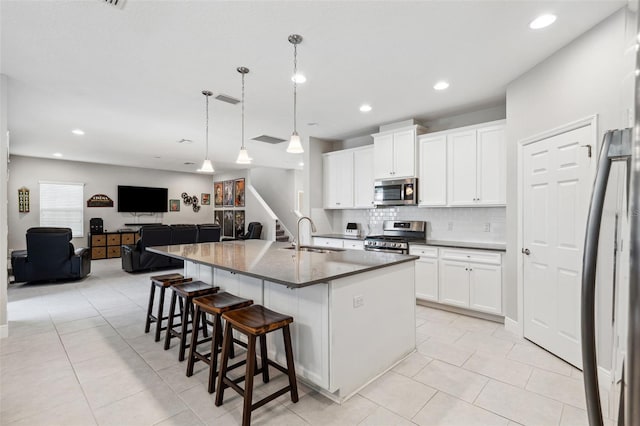 kitchen featuring white cabinets, appliances with stainless steel finishes, a breakfast bar, a sink, and backsplash