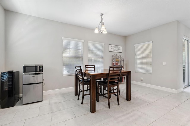 dining room featuring an inviting chandelier, wine cooler, baseboards, and light tile patterned flooring