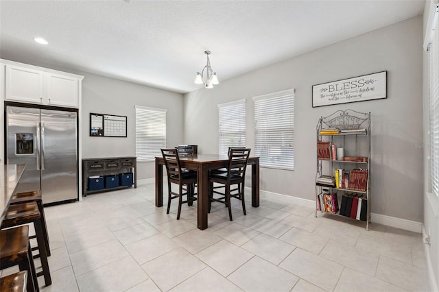 dining area featuring a chandelier, a textured ceiling, baseboards, and light tile patterned floors