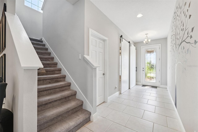 entrance foyer with light tile patterned floors, a barn door, recessed lighting, baseboards, and stairs