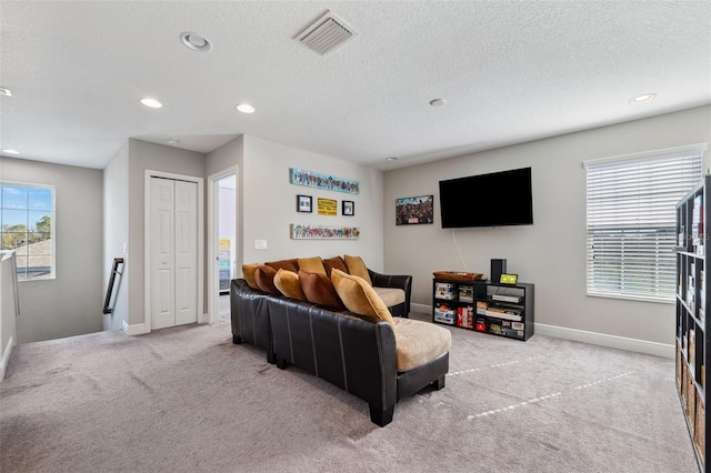 living area featuring a textured ceiling, carpet, visible vents, and baseboards