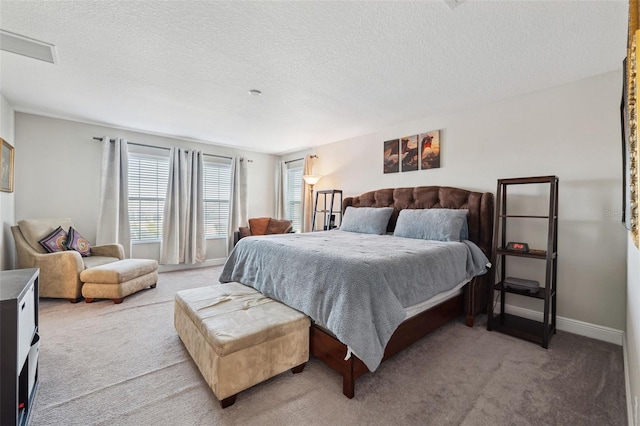 bedroom featuring light carpet, a textured ceiling, and baseboards