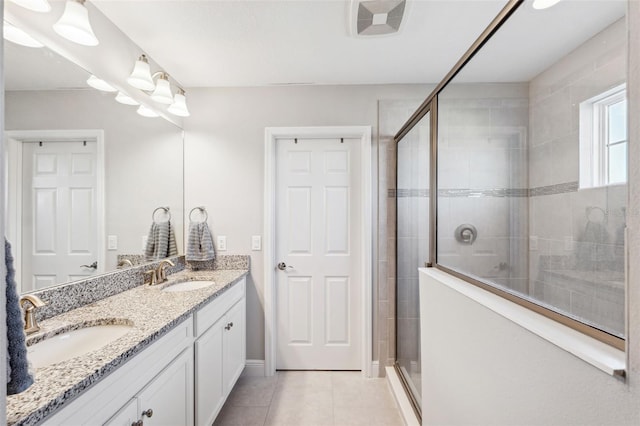 full bath featuring double vanity, a shower stall, a sink, and tile patterned floors