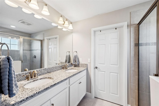 full bath with double vanity, a shower stall, visible vents, and a sink