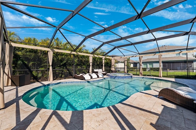 view of pool featuring a pool with connected hot tub, a patio, a lanai, and fence