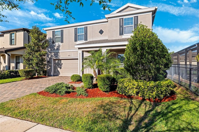 view of front of property with an attached garage, fence, decorative driveway, and stucco siding