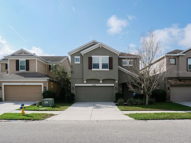 view of front of house featuring a garage, concrete driveway, and stucco siding