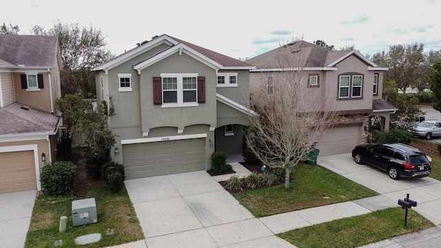 traditional-style home featuring a garage, concrete driveway, and stucco siding