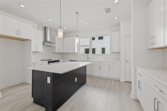 kitchen with light countertops, white cabinets, visible vents, and wall chimney exhaust hood