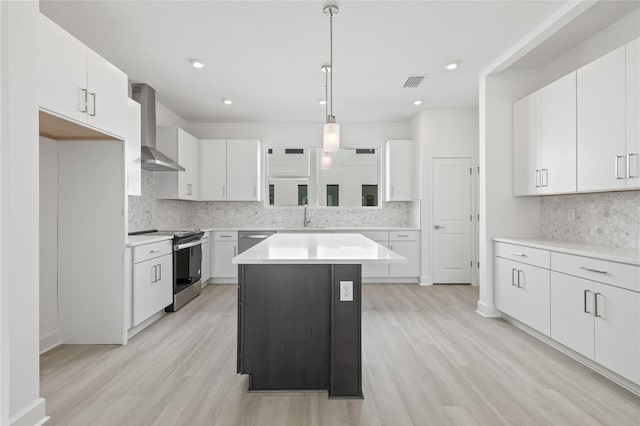 kitchen featuring wall chimney exhaust hood, light wood finished floors, visible vents, and stainless steel appliances